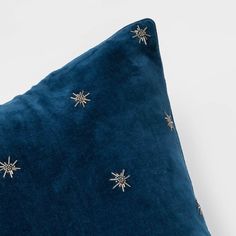 a blue velvet pillow with gold stars on the front and back, against a white background