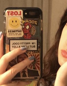 a woman holding up a cell phone with stickers on it