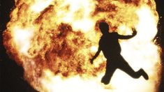 a man is running in front of a large fireball