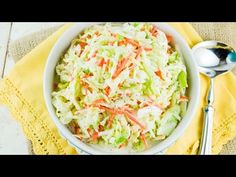 a white bowl filled with coleslaw on top of a yellow napkin next to a spoon