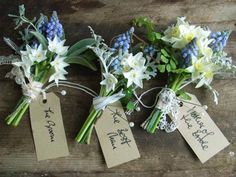 three bouquets of flowers with tags attached to them sitting on a wooden table together