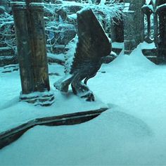 an owl statue sitting in the middle of a snowy forest