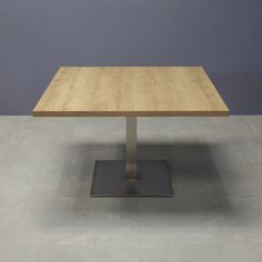 a square wooden table sitting on top of a metal base