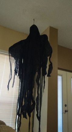 a black cloth hanging from the ceiling in a living room with blinds on the windowsill