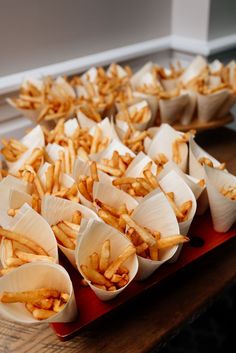 this french fry bar is set up with small paper cones of french fries, which are in boardwalk style french fry holders Party Snacks Wedding, Fries Bar Wedding, Midnight Snack At Wedding, Fries At Wedding, Cocktail Wedding Food Ideas, French Fry Wedding Bar, Reception Treat Ideas, Wedding French Fry Bar, Wedding Fast Food Bar