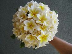 a hand holding a bouquet of white and yellow flowers in it's left arm