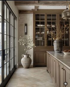 a large vase with flowers in it sitting on a kitchen counter next to a window