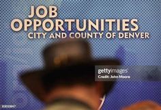 a blurry image of a man wearing a hat and holding a microphone in front of a sign that says job opportunity cities and county of denver