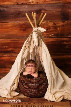 a baby is sleeping in a basket under a teepee