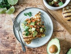 an avocado and chicken dish on a plate with a fork next to it