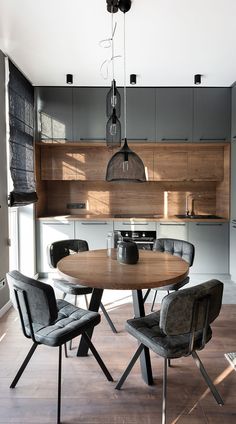 a dining room table and chairs in front of a kitchen with wooden cabinets, gray walls and wood flooring