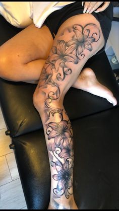 a woman laying on top of a black couch next to her legs with tattoos on them