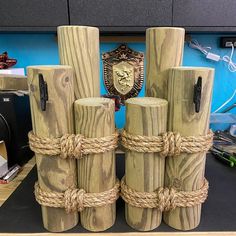 several wooden posts with rope wrapped around them and a shield on the wall behind them