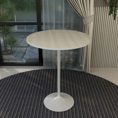 a round white table sitting on top of a carpeted floor next to a window