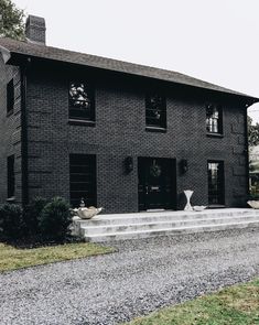 a black brick house with steps leading up to the front door