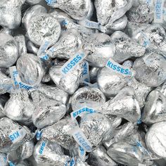 silver foiled chocolate hearts are stacked on top of each other, with the words kisses printed on them