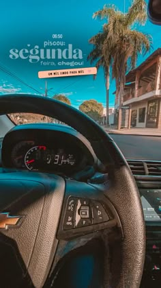 the dashboard of a car on a street with palm trees and buildings in the background