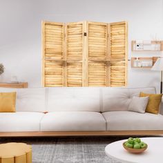 a living room with white couches and wooden shutters