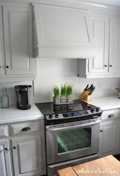 a kitchen with white cabinets and stainless steel stove top oven in the middle of it