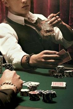 a man sitting at a table with cards and playing chips