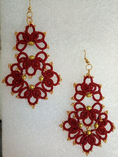 two pairs of red and gold beaded earrings on a white surface, with beads hanging from them