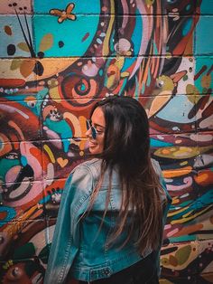 a woman standing in front of a colorful wall