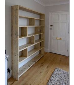 an empty bookcase in the corner of a room with wood floors and white walls