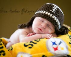 a baby wearing a football hat laying on top of a blanket with his eyes closed