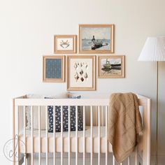 a white crib with pictures on the wall above it and a lamp next to it