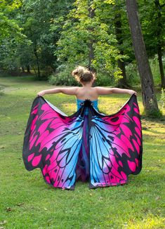 a woman in a butterfly print dress standing on the grass with her back to the camera