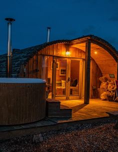 a hot tub sitting on top of a wooden deck next to a building at night