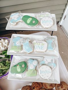 two trays filled with decorated cookies on top of a table next to each other