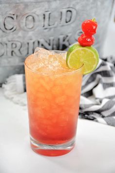 a red drink with lime and a cherry on top