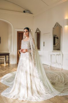 a woman in a white wedding dress standing on a wooden floor with her veil pulled back