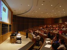 a lecture hall full of people sitting at desks