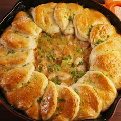 a casserole filled with meat and cheese in a black dish on top of a wooden table