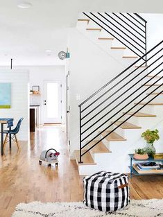 a living room filled with furniture and a stair case next to a wooden floor covered in white rugs