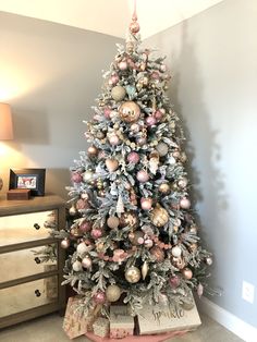 a decorated christmas tree in a living room next to a dresser with presents on it