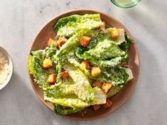 a plate full of lettuce and croutons next to a glass of water