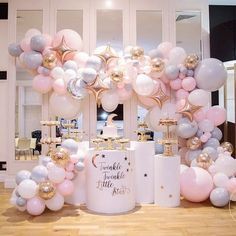 a table topped with lots of balloons next to a white vase filled with pink and silver items