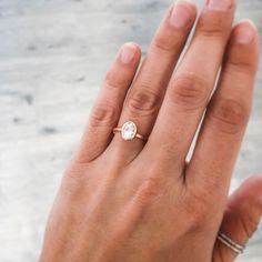 a woman's hand with a diamond ring on her left hand and the other hand holding an engagement ring