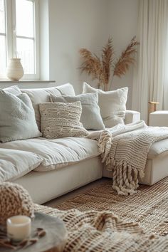 a living room filled with lots of pillows and blankets on top of a couch next to a window