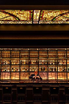 an empty bar with many bottles on the shelves and a stained glass window above it