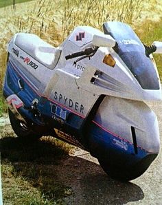 a white and blue motorcycle parked on the side of a road next to tall grass