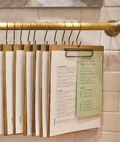 several menus are hanging on a rack in a kitchen with white tiles and gold handles