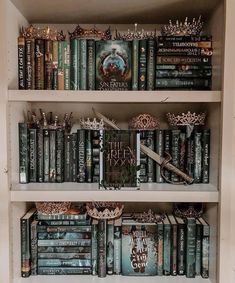 a book shelf filled with lots of books and crown figurines on top of them