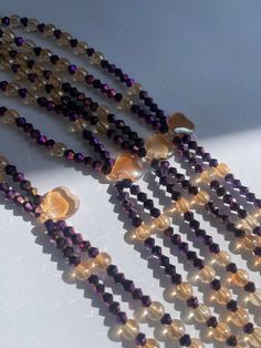 Double Strand Waist Bead, a stunning blend of purple crystal glass beads with elegant gold and brown accents. Why You'll Love It: Exquisite Sparkle: Beautiful purple crystal glass beads create a radiant, eye-catching shimmer. Elegant Accents: Gold and brown crystal glass beads add a touch of luxury and sophistication. Perfect Fit: The adjustable double strand design ensures comfort and a secure fit for all body types. Cultural Beauty: This piece reflects the rich heritage of Ivorian craftsmanshi Gold Beaded Necklaces With Heart Beads For Party, Gold Beaded Necklace With Heart Beads For Parties, Adjustable Gold Crystal Glass Necklace, Purple Glass Beaded Necklaces With Round Beads, Gold Beaded Glass Crystal Necklaces, Purple Glass Beaded Necklace With Round Beads, Gold Amethyst Beaded Necklace With Faceted Beads, Gold Amethyst Crystal Necklace With Faceted Beads, Purple Glass Beaded Necklace