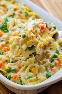 a casserole dish with noodles, peas and carrots