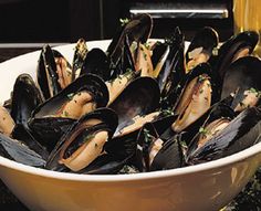 a white bowl filled with mussels on top of a table