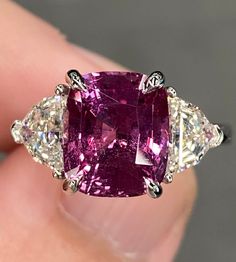 ALL THESE PHOTOS WERE TAKEN WITH AN ORDINARY IPHONE & HAVE NOT BEEN EDITED OR ENHANCED IN ANY WAY. The Center Stone is a Spectacular Natural GIA Certified 5.03 Ct Vivid Purplish Pink Cushion Cut Sapphire that measures approx 10.3 x 8.7 mm & was mined in Madagascar. It Checks all the boxes with phenomenal cutting, Beautiful Color, & amazing clarity.  The Mounting was 100% Custom Made Specifically for this Remarkable Sapphire out of Solid Platinum & is Stamped. It Features a matching pair of Natural Earth Mined G-H VVS-VS Epaulette Cut Diamonds that weigh 1.32 Ct Combined. They are both Very White (Near Colorless) Diamonds that are 100% clean to the eye as well as clean under 10x magnification. They are both Crystal Clear, Super Lively Diamonds that are Full of Brilliance, Fire, Spark & Flas Elongated Cushion Three Stone, Elongated Cushion, Vvs Diamond, Platinum Diamond Rings, Colorless Diamond, Royal Jewels, Platinum Ring, Pink Ring, Pink Diamond